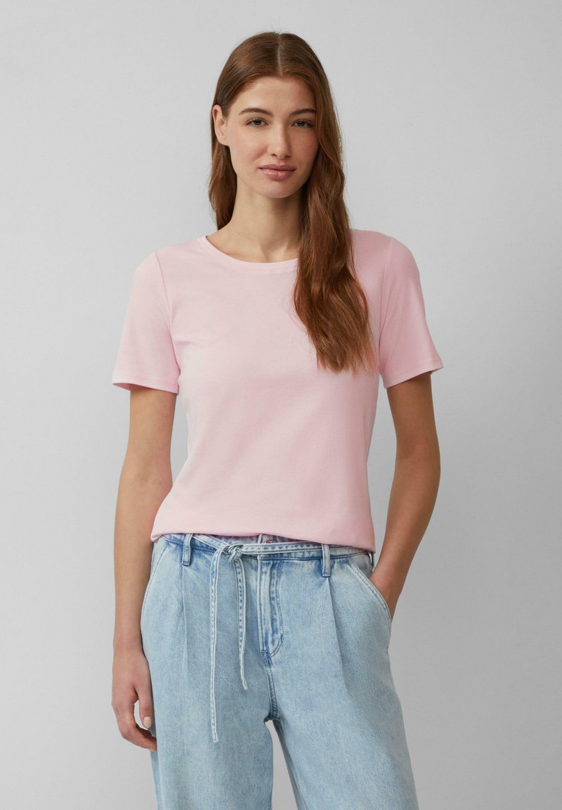 Lichtroze t-shirt met korte mouwen van katoen, voorzien van een ronde halslijn en een comfortabele pasvorm, gecombineerd met lichtblauwe high-waisted jeans.