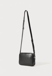 Borsa a tracolla in pelle nera con forma rettangolare, tracolla regolabile, superficie liscia e chiusura con zip. Design minimalista senza decorazioni visibili.