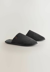 Sorte fløjlsklipklapper med en blød grå indvendig, lav profil og tekstureret ribbet design. Fleksibel sål og minimalistisk brandingdetalje.