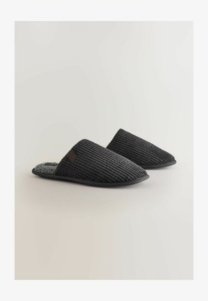 Černé manšestrové pantofle s měkkým šedým interiérem, nízkým profilem a texturovaným žebrovaným designem. Flexibilní podešev a minimalistic detail brandingu.