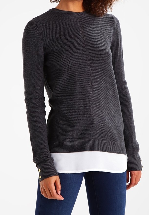 Tummanharmaa ribbikuvioinen neulepaita, jossa on pitkät hihat, pyöreä kaula-aukko ja nappikoristeet hihansuissa. Kerrostettu valkoisen paidan päälle.