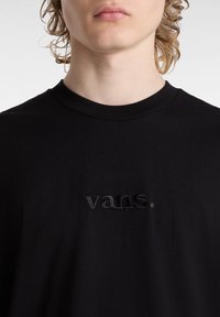 T-shirt in cotone nero con logo "vans." ricamato dello stesso colore. Collo rotondo, texture morbida, vestibilità rilassata.
