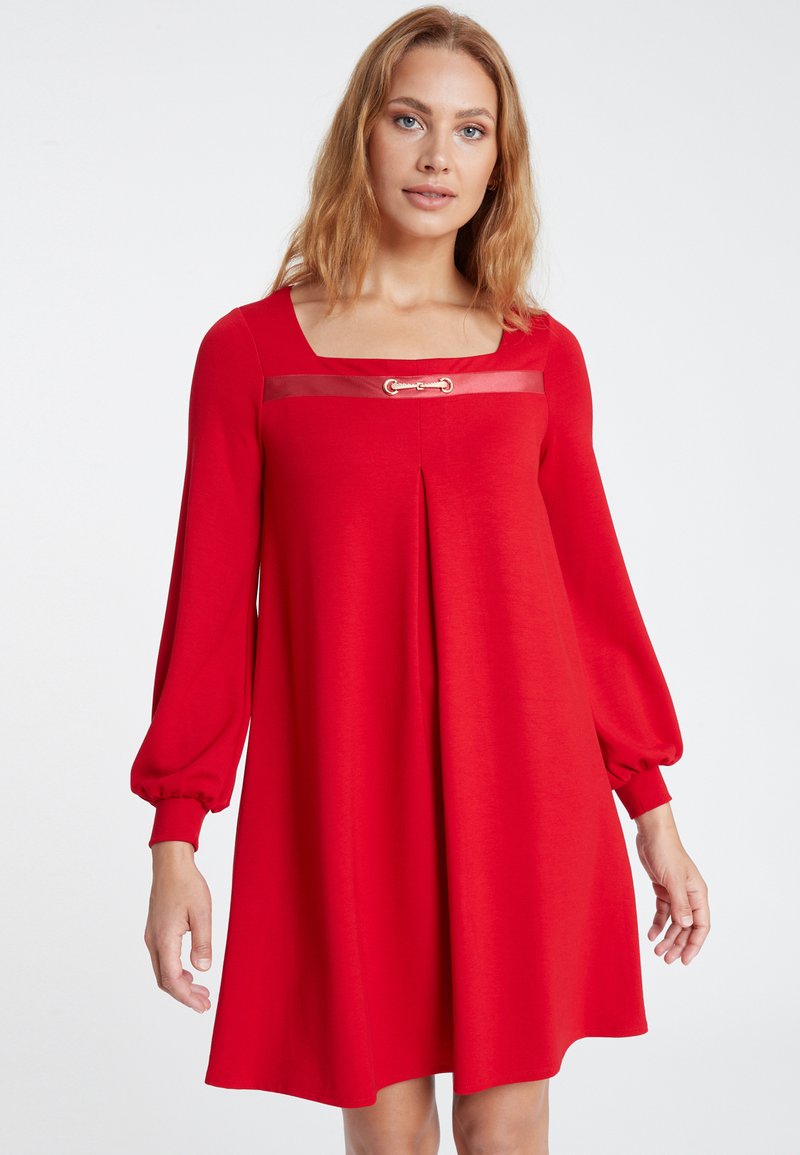 Rotes langärmliges Kleid mit quadratischem Ausschnitt, goldene Hardware-Akzent am Dekolleté, gefältetes Design und schmal zulaufende Manschetten. Weicher, glatter Stoff.