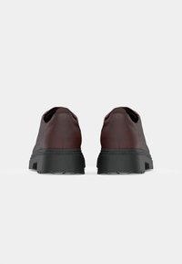Pantofi din piele maro cu spate rotunjit, talpă din cauciuc negru și accente texturate. Design curat cu detalii minime vizibile.