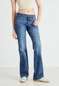 Flared blue jeans made of denim with a faded finish, five-pocket design, button fly, and subtle stitching details.