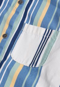 Chemise rayée aux couleurs bleue, verte, jaune et blanche ; comprend une poche poitrine avec des rayures horizontales et des boutons métalliques.