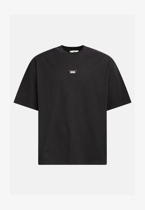 Black cotton t-shirt with a round neckline, short sleeves, and a small graphic label on the chest. Simple, relaxed fit design.