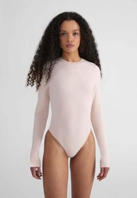 Body a maniche lunghe in morbido tessuto rosa, con collo alto e design aderente. Texture liscia, cuciture minime e nessun hardware visibile.