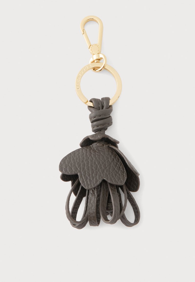 Porte-clés en métal doré avec pompon en cuir gris foncé en forme de pétales de fleurs et boucles suspendues en dessous.