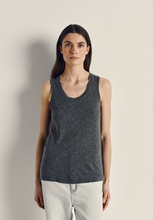 Sleeveless, dark gray tank top made of soft fabric, featuring a scoop neckline and a relaxed fit, paired with light blue jeans.