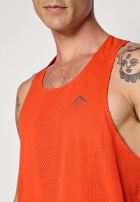 Orange sleeveless athletic tank top made of breathable mesh fabric, featuring a small blue logo accent and a relaxed fit.