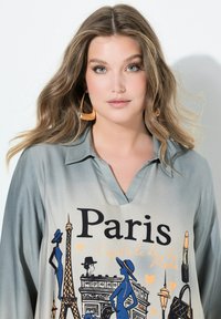 V-hals, oversized skjorte i gradient blå-grøn stof med et Paris grafisk design, inklusive Eiffeltårnet og modeillustrationer.