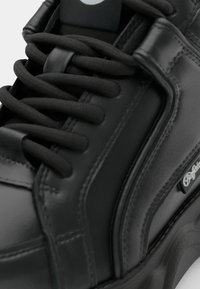 Zwarte leren sneakers met dikke zwarte veters, gewatteerde kraag en verstevigde stiksels. Heeft een logo-accent en een gladde, glanzende oppervlakte.