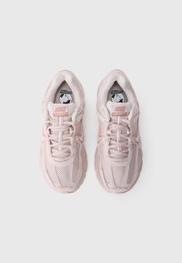 Sneakers in rete rosa con un design testurizzato. Presentano lacci, un marchio sulla linguetta e una suola leggera. Accenti in un rosa leggermente più scuro.