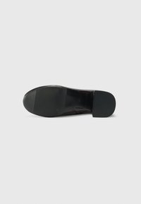 Suela de zapato de cuero negro con un patrón texturizado y diseño plano. Incluye una punta redondeada con un acabado suave y suela de goma duradera.