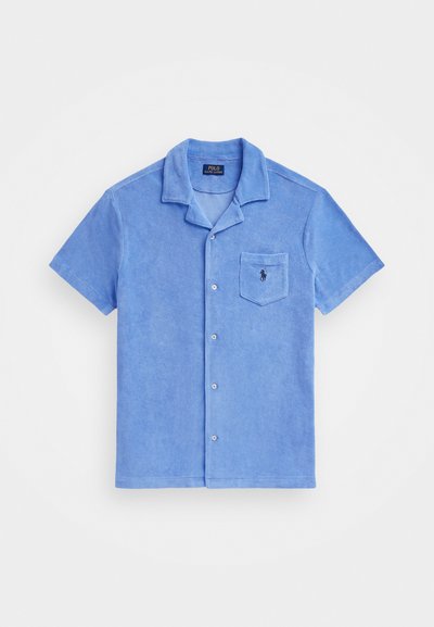 Šviesiai mėlynas trumpomis rankovėmis marškinys, pagamintas iš terry audinio, su išpjauta apykakle, mygtukų užsegimu ir krūtinės kišene su mažuoju logotipu.