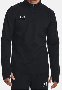 Svart zip-up-pullover i mjukt tyg med långa ärmar. Har hög krage och vit Under Armour-logotyp på bröstet.