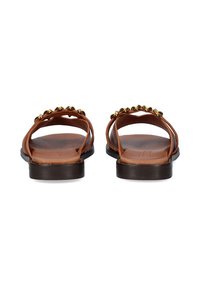 Sandalias de cuero marrón con suela plana, que presentan dos correas anchas y tachuelas doradas decorativas a lo largo de la parte superior. Textura suave, diseño con parte trasera abierta.