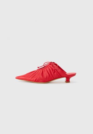 Mule de cuero rojo con punta afilada, diseño de parte superior gathered y un tacón bajo y transparente. Presenta un cierre con cordón en el tobillo.