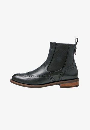Bottine en cuir noir avec détails brogue, panneau latéral élastique, languette de tirage et talon empilé marron.