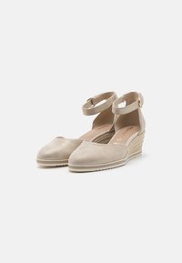Zapatos de cuña en ante beige con punta redondeada, correa al tobillo y detalles de yute trenzado en el tacón. Textura suave y diseño minimalista.