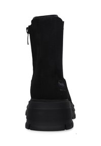 Schwarze Wildleder-Stiefeletten mit glatter Textur, ausgestattet mit einem seitlichen Reißverschluss und einer dicken Gummisohle für Stabilität. Logodetail an der Ferse sichtbar.
