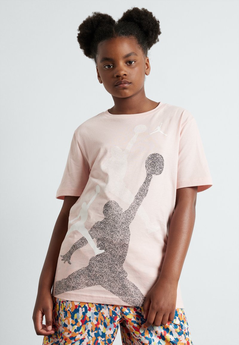 Camiseta de algodón rosa con un gráfico en blanco y negro de un jugador de baloncesto en acción. Mangas cortas y corte relajado.