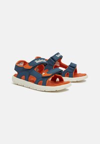 Marineblaue und orangefarbene Sandalen mit Klettverschlussriemen, offenes Zehendesign, strukturiertes Fußbett und weißer Gummisohle; mit ausgeschnittenen Akzenten.