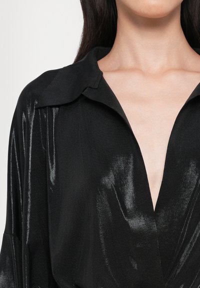 Black blouse with a shiny, smooth texture. Features a wide collar, deep V-neckline, and loose fit, emphasizing draped folds.