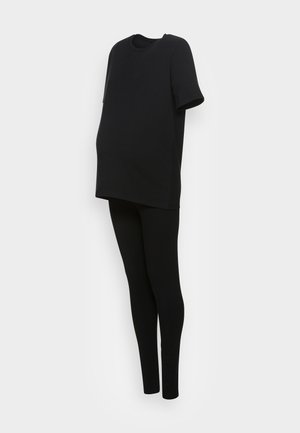 Conjunto de maternidad negro con una blusa de manga corta y holgada y leggings ajustados, mostrado contra un fondo claro y liso.