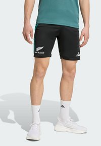 Black athletic shorts with teal accents, featuring the "ALL BLACKS" logo and an Adidas logo. Worn with white socks and white sneakers.