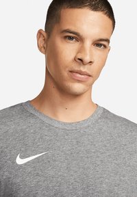 Grijze t-shirt met korte mouwen gemaakt van een katoenmix. Voorzien van een wit Nike logo op de borst en een ronde halslijn. Soepele textuur.