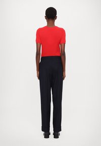 Top corto a maniche corte di maglia rossa abbinato a pantaloni a vita alta blu navy, con una vestibilità dritta e risvolti alle maniche. Tessuto liscio, design minimalista.