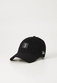 Black corduroy cap with rounded crown, curved visor, and embroidered logo patch. Features contrasting stitching and adjustable strap.