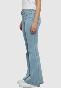 Lichtblauwe flared jeans van denim, met een aangesloten taille, lichte slijtage en subtiele stiksels op de achterzakken.