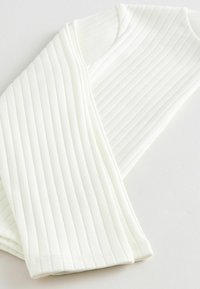 White ribbed long-sleeve top displaying vertical lines and a soft texture. Features a rounded neckline and fitted cuffs.