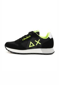Sneaker sportivo nero con accenti verde neon, parte superiore in suede e tessuto, punta arrotondata, suola intermedia bianca spessa e suola in gomma con motivo.
