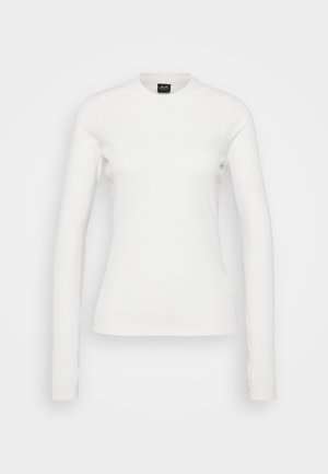 Maglietta a maniche lunghe bianca aderente con girocollo, con logo discreto sul petto e texture a coste, esposta su uno sfondo semplice.
