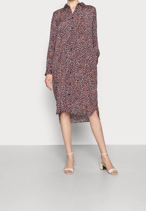 Robe longue à boutons en bleu marine, rouge et blanc avec un motif éparpillé. Tissu léger, col classique et fente sur le côté pour plus de liberté de mouvement.