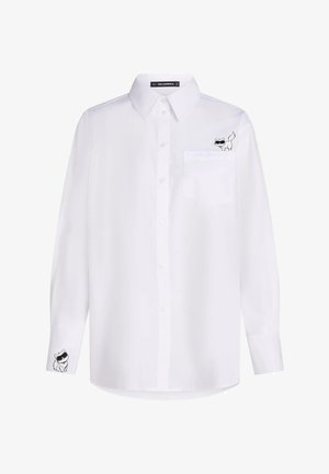 Camicia bianca a maniche lunghe con bottoni con due piccole illustrazioni di gatti neri che indossano occhiali da sole, una sulla tasca del petto e una sul polsino.