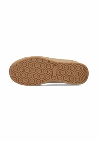 Suola di scarpa in gomma color tortora con una trama a zigzag che presenta forme esagonali e accenti circolari, progettata per offrire trazione e durata.