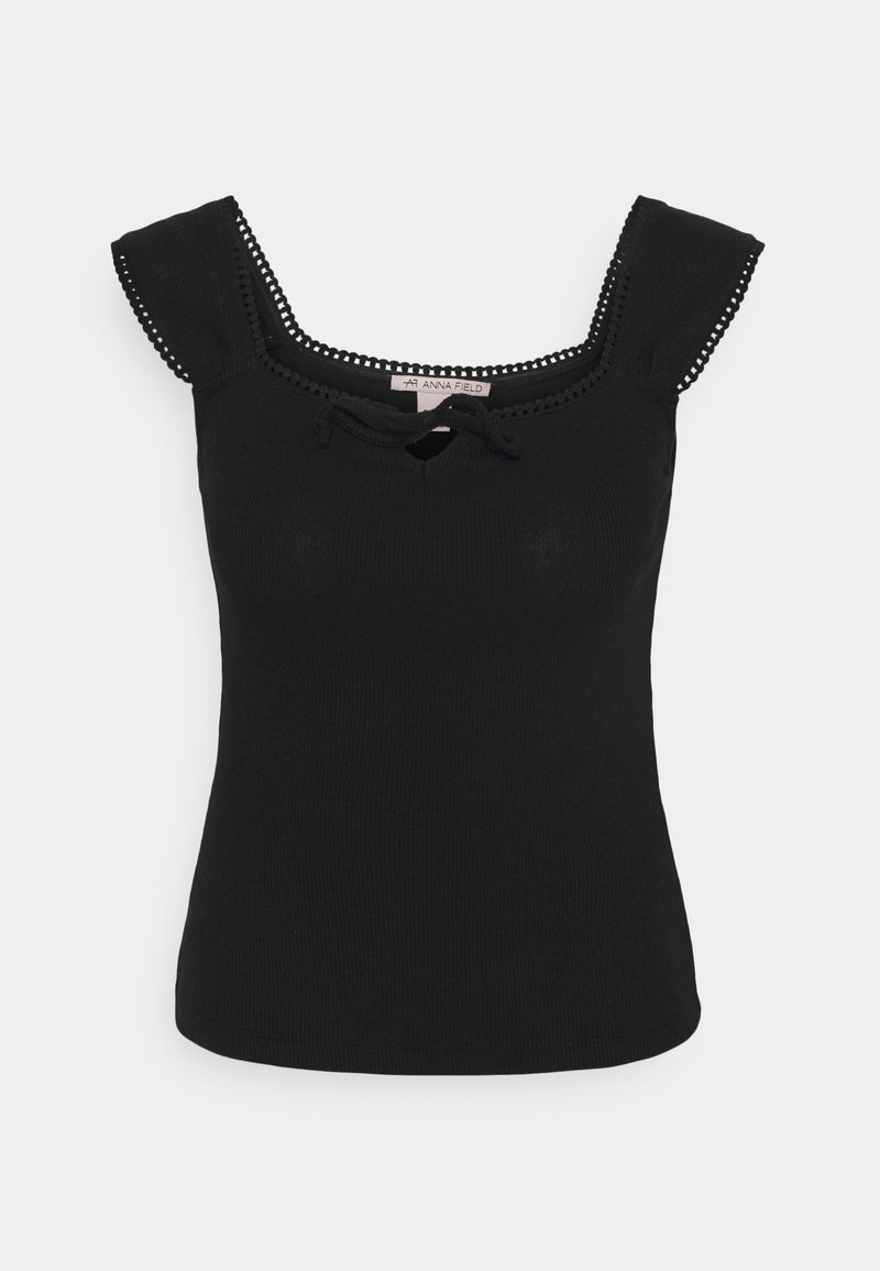 Canottiera nera a costine con rouches sulle spalle, scollatura quadrata e un piccolo dettaglio a chiave sul davanti. Presenta cuciture decorative lungo il collo.
