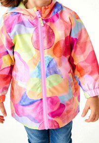 Veste de pluie colorée avec un design abstrait rose, orange et bleu. Elle comprend une fermeture éclair à l'avant et des poignets élastiques pour un ajustement optimal.