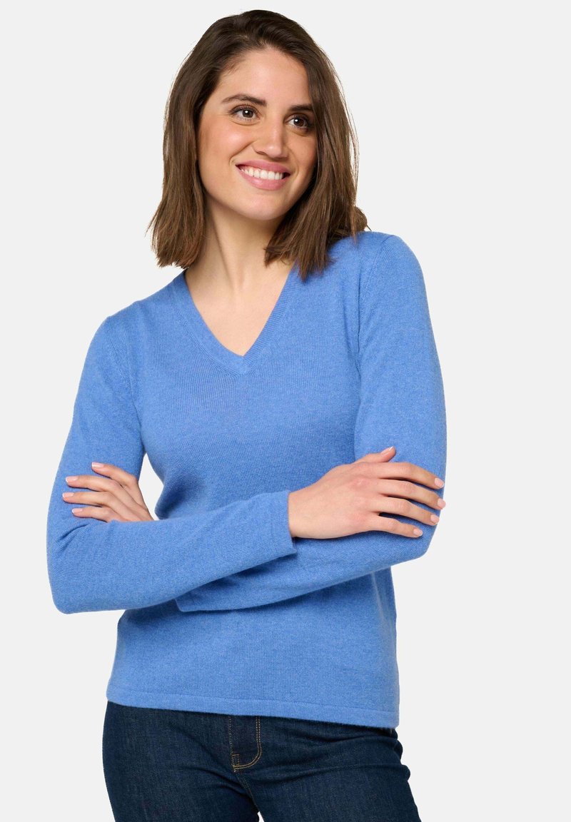 Pull bleu clair à col en V en tricot doux ; manches longues et poignets côtelés ; porté avec un jean foncé.