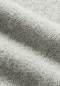 Tessuto grigio chiaro, texturizzato, con una superficie morbida e pelosa. Pattern a coste visibile e lievi variazioni di colore, che indicano materiale in lana.