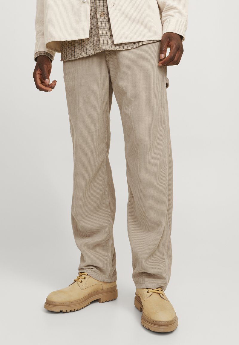 Beige corduroy pants with a straight leg fit, featuring vertical ridges and side pockets, paired with tan lace-up boots.