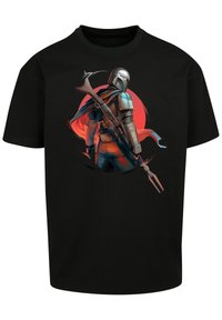 Black cotton t-shirt featuring a colorful graphic of a helmeted figure with a cape and weapon, set against a red circular background.