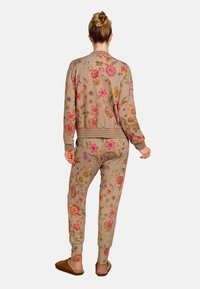 Beige trainingspak met bloemenborduursels en geribde manchetten en tailleband. Heeft kleurrijke bloemenpatronen, ontworpen voor een relaxte pasvorm.