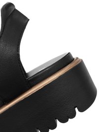 Sort læderplatform-sandal med tyk, tekstureret sål og åben bagrem, vist tæt på mod hvid baggrund.