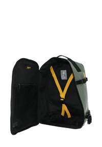 Sac à dos vert et noir avec des bretelles jaunes, offrant un intérieur spacieux, une poche zippée et une boucle latérale pour ajustement.